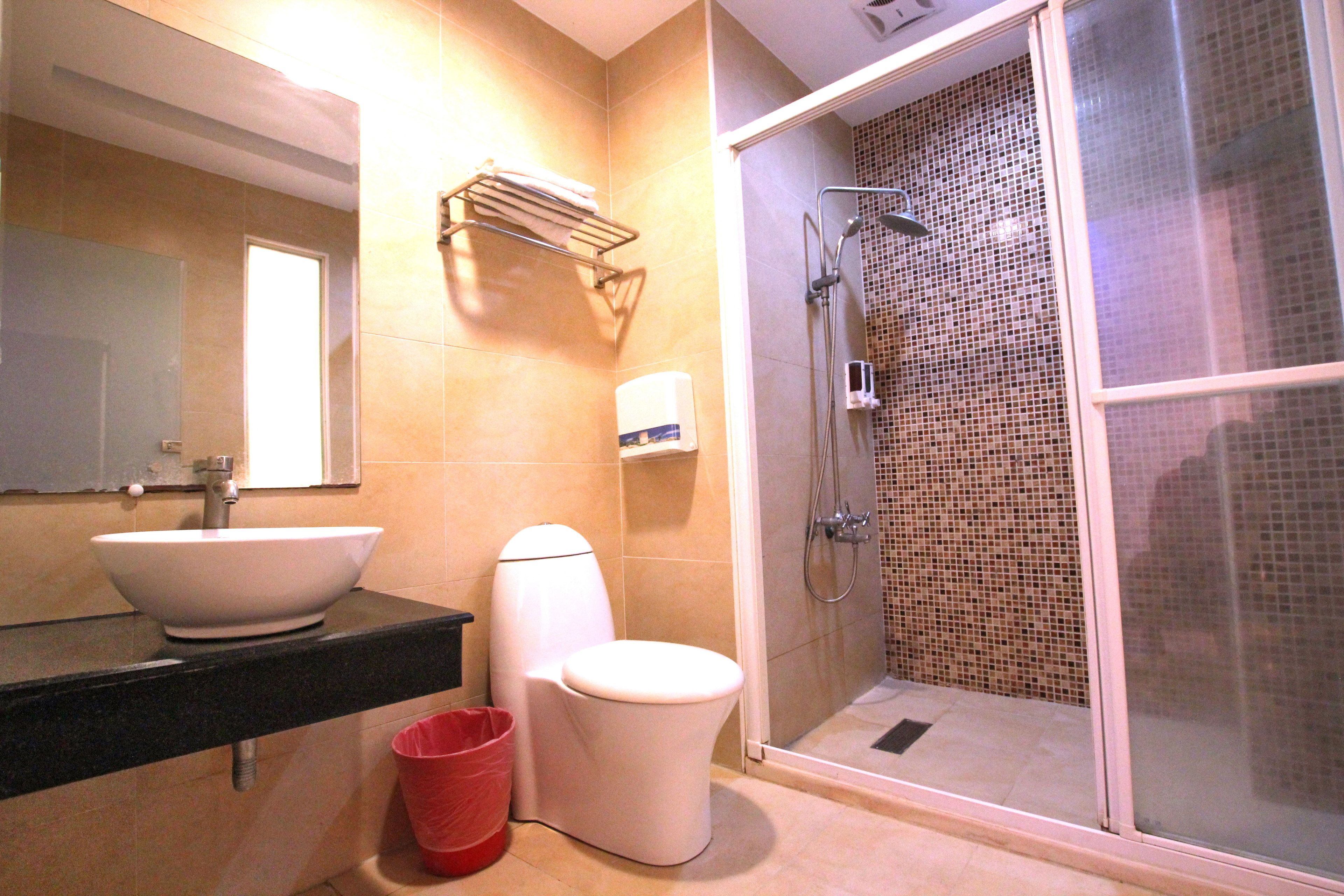A bathroom with a large sink, toilet, and shower.