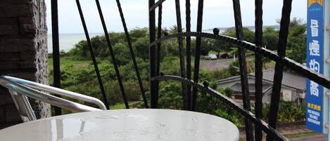 A balcony with a white table and chairs, a view of the sea, and a sign for a restaurant.