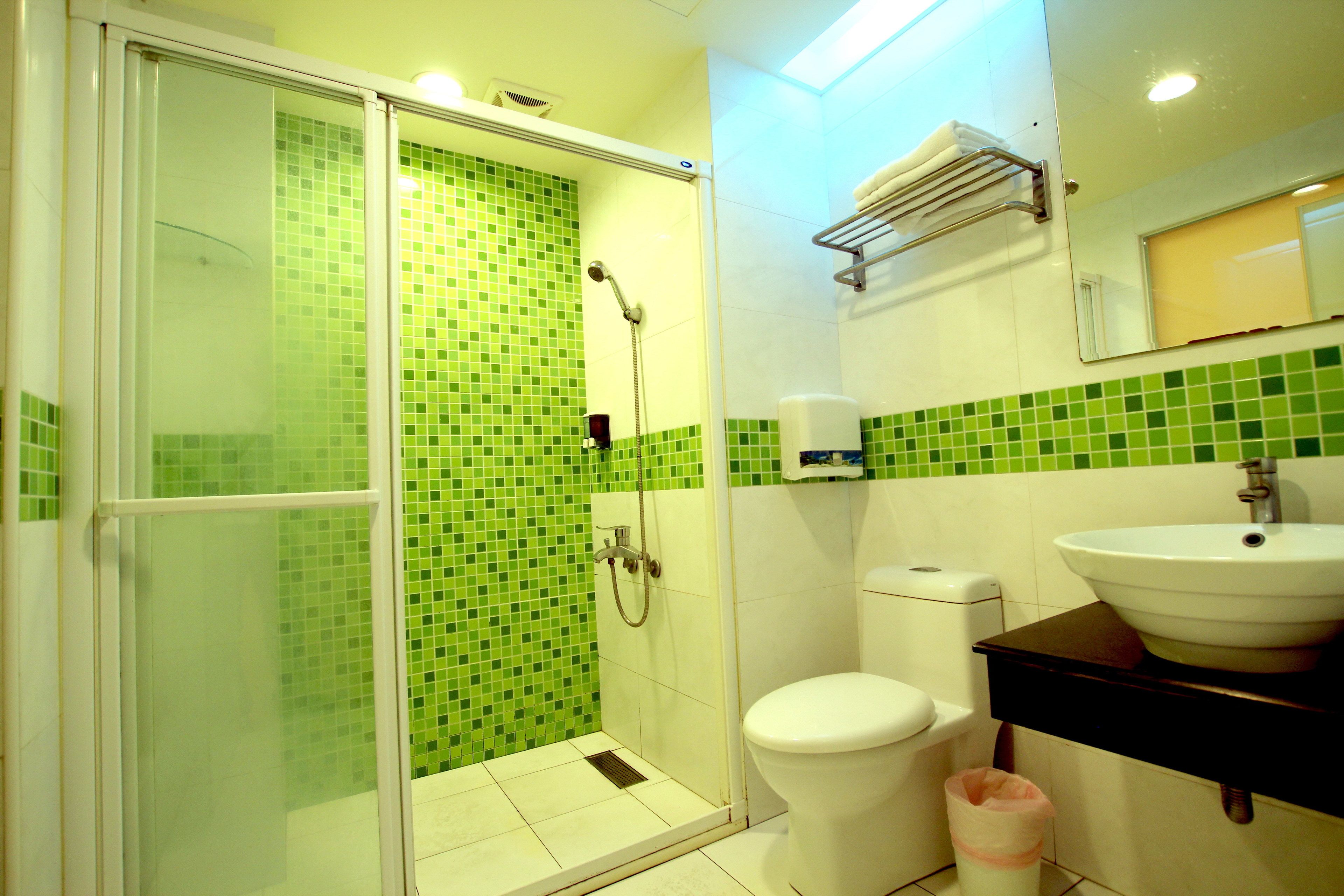 A bathroom with a glass-enclosed shower, a white toilet, and a sink with a mirror above it.