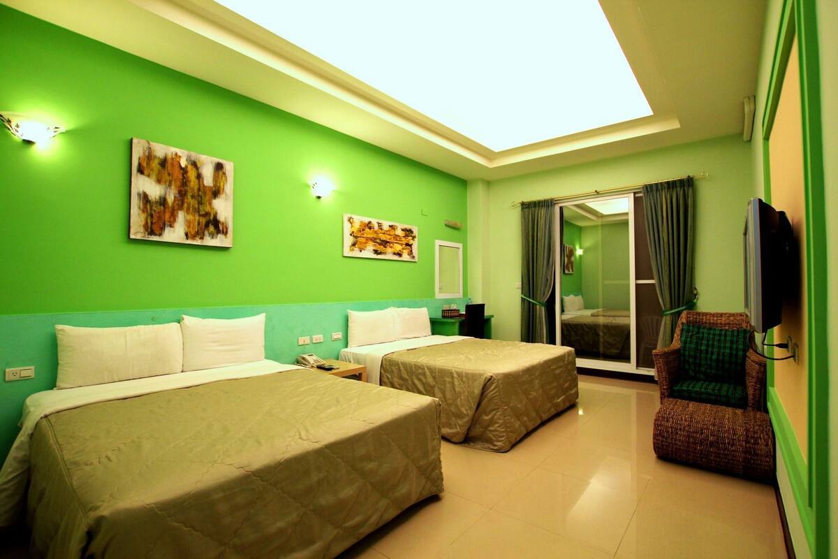 A hotel room with two beds, a television, a chair, and artwork on the walls.