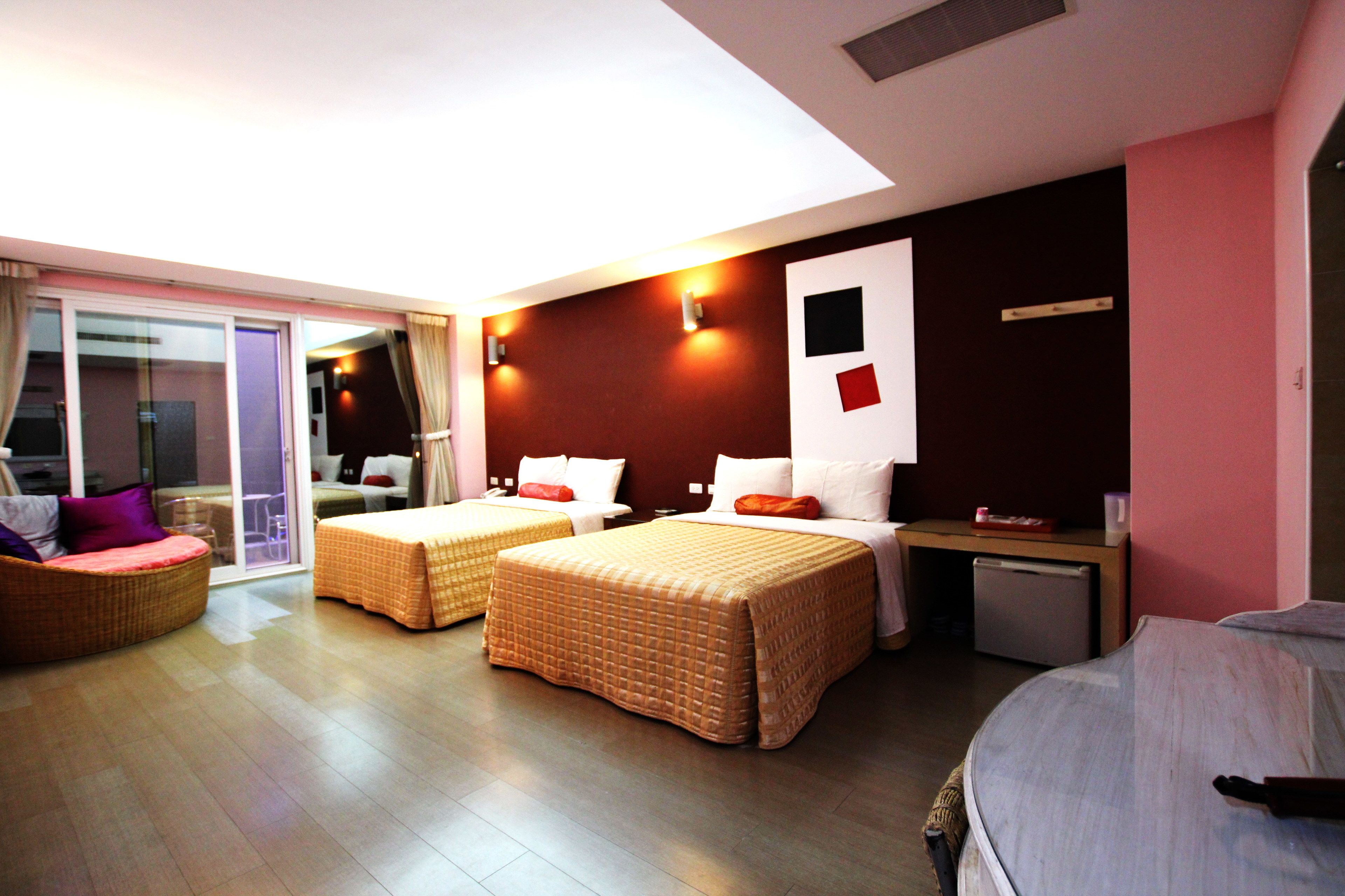 A hotel room with two single beds, a sofa, a small table, and a refrigerator.