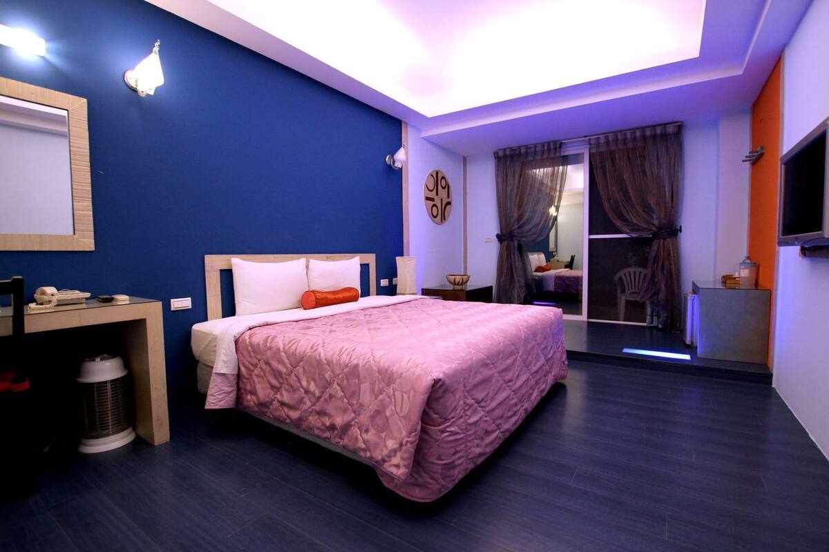 A bedroom with a bed, bedside table, and a desk with a chair.