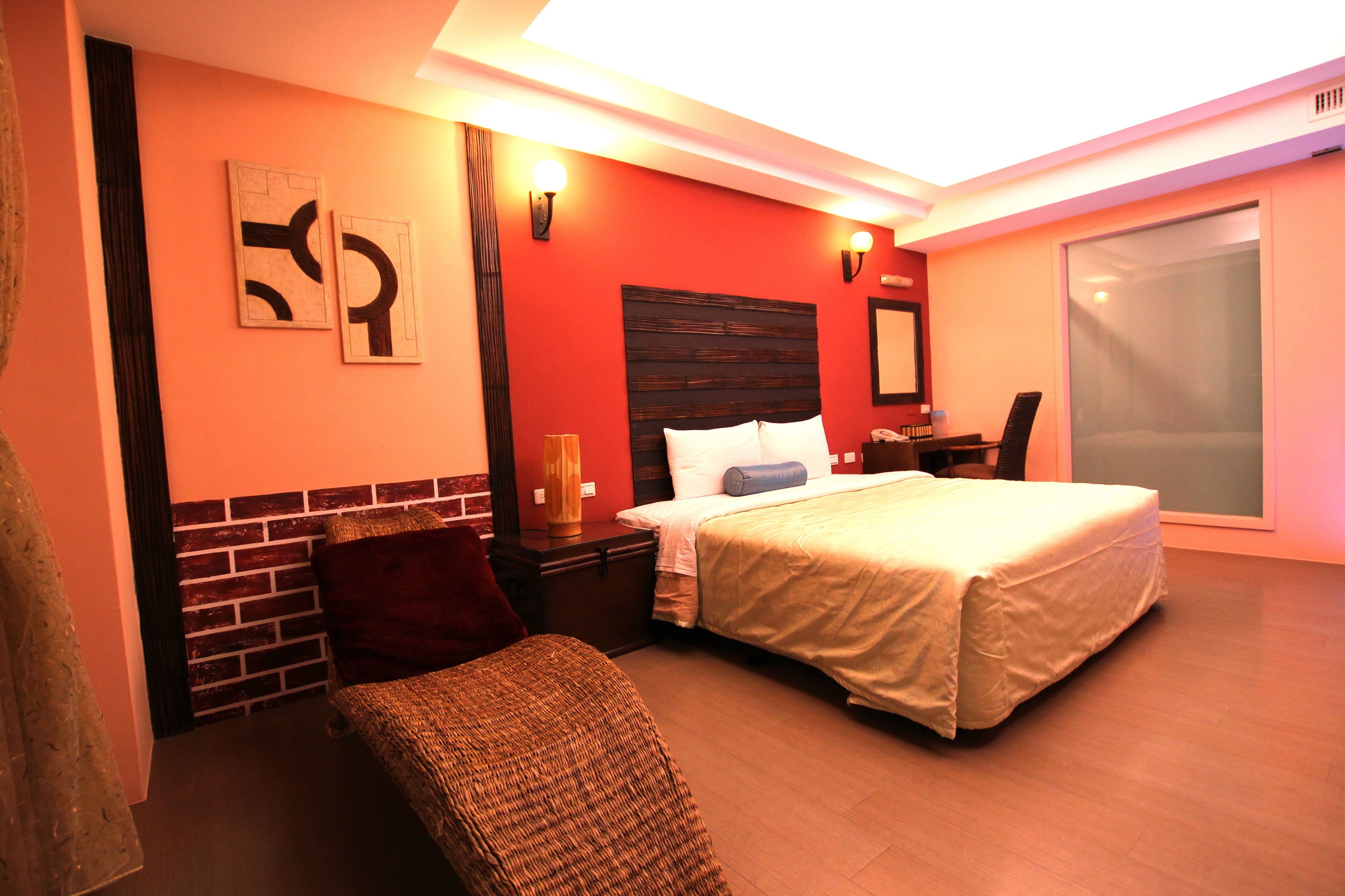A hotel room with a bed, a chair, a nightstand, and a desk.