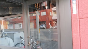 A glass door entrance to a building with a bicycle parked outside. - SAPPORO GUEST HOUSE NARIYA - Hostel (Sapporo)