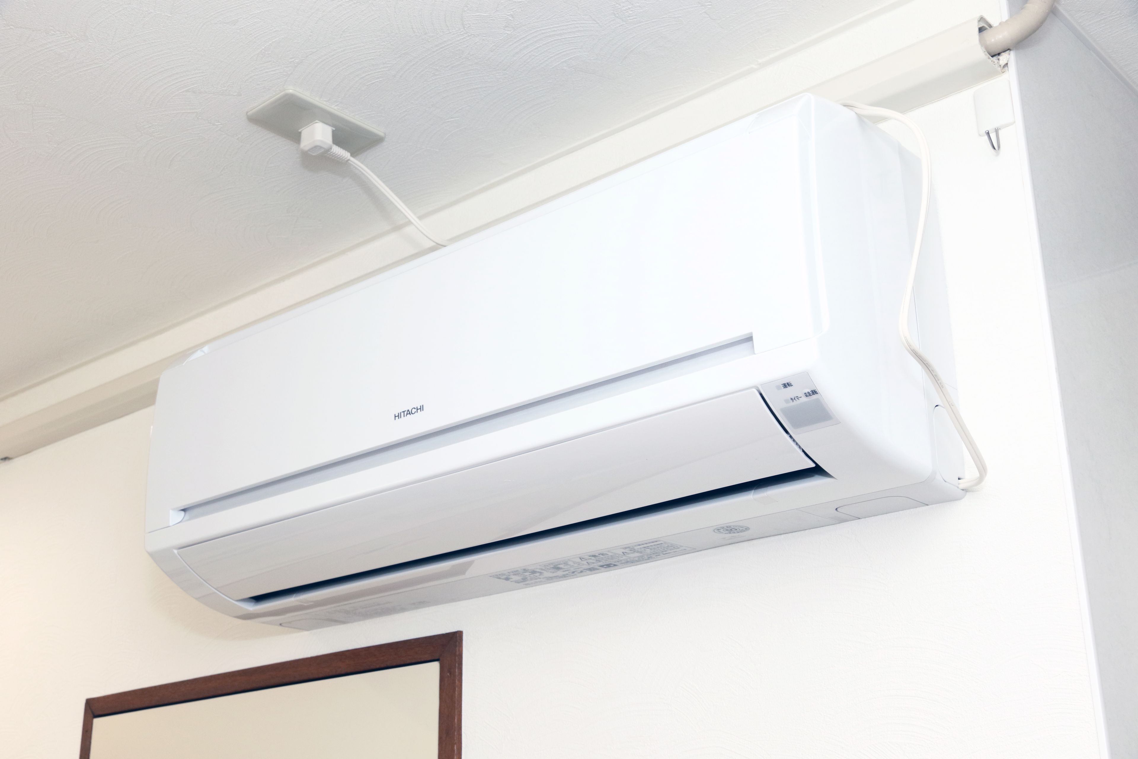 A wall-mounted air conditioner with a control panel and a power cord.