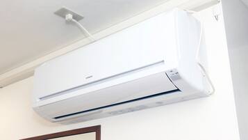 A wall-mounted air conditioner with a control panel and a power cord.
