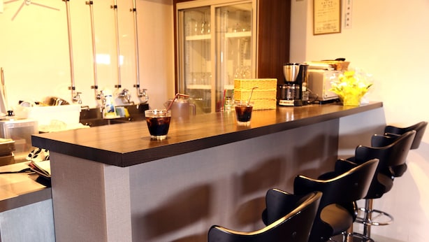 A bar area with stools, a counter, and a coffee machine. - SAPPORO GUEST HOUSE NARIYA - Hostel (Sapporo)