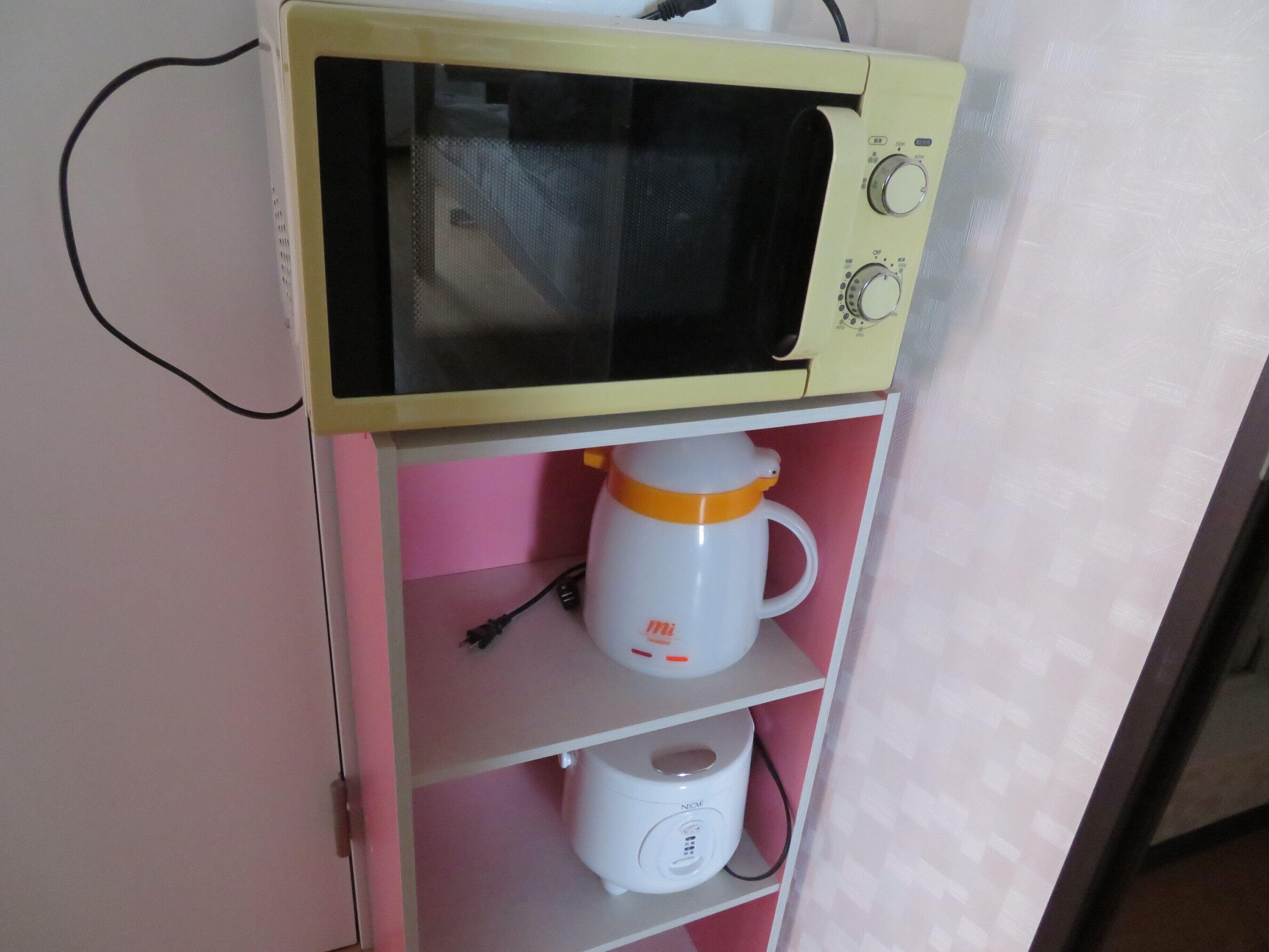 Een magnetron op een plank, met een koffiezetapparaat en een rijstkoker eronder.