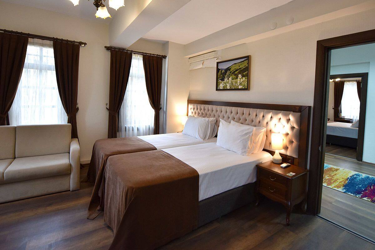 A hotel room with a double bed, a sofa, a nightstand, and a large mirror.