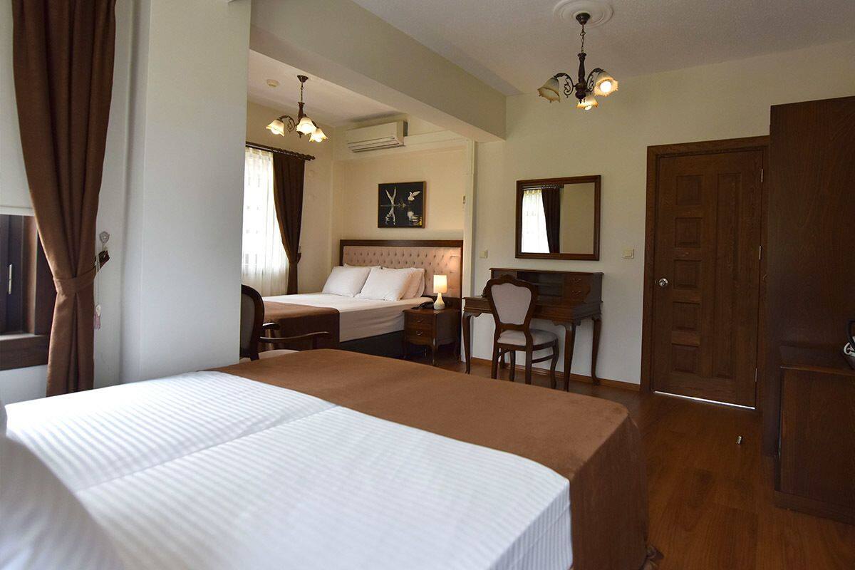 A hotel room with a large bed, a desk with a chair, a wardrobe, and a mirror on the wall.