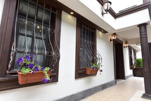 A building facade with large windows, decorative ironwork, and potted plants. - Zagnospasa Konaklari (Trabzon)