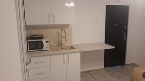Cuina compacta amb microones, rentaplat i armaris blancs.