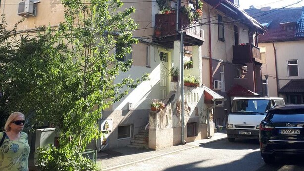 Un edifici de dues plantes amb teulada vermella, una escala que mena al pis superior i un cotxe aparcat a la façana.