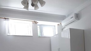 Un dormitori amb llit, armari, ventilador de sostre i finestra.