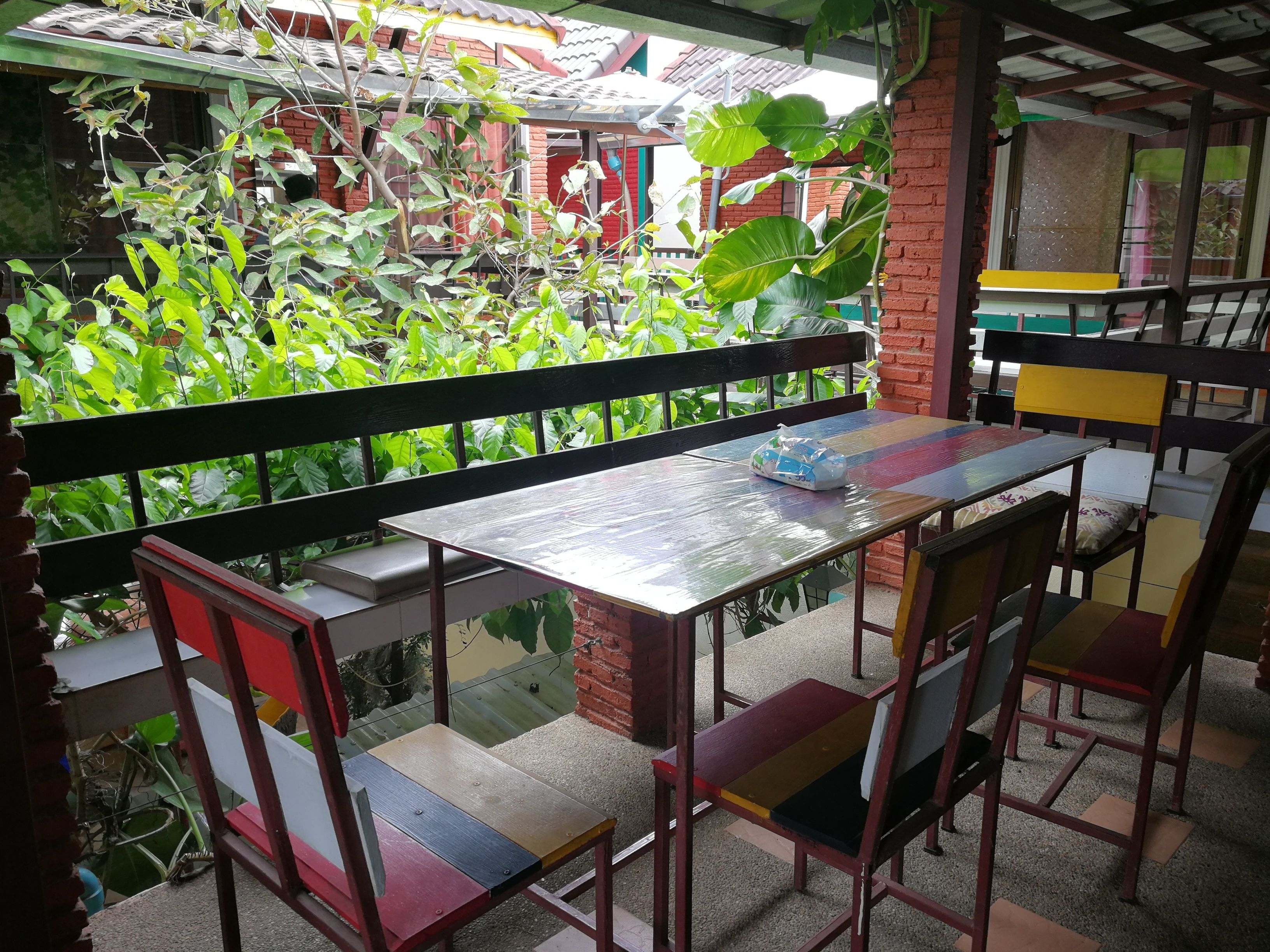 A balcony with a table and chairs, surrounded by lush green plants.
