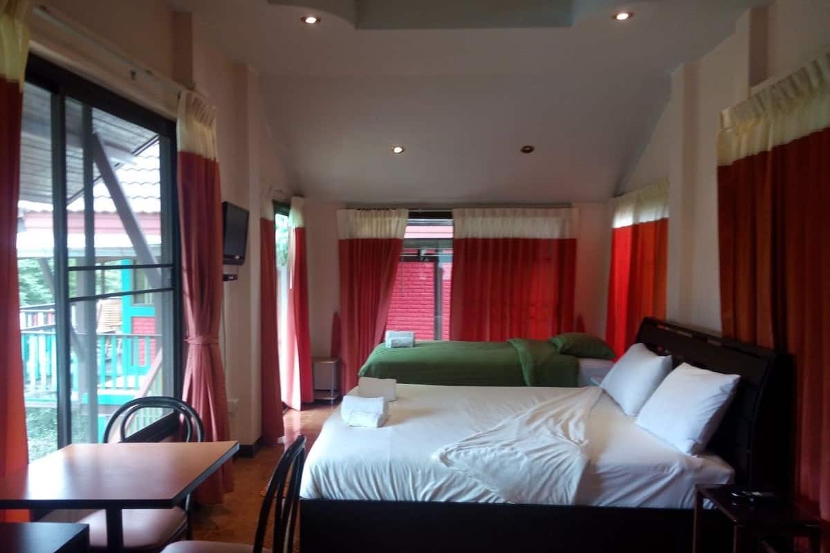 A hotel room with a bed, a desk, and a chair. There is a window with curtains and a view of an outdoor area.