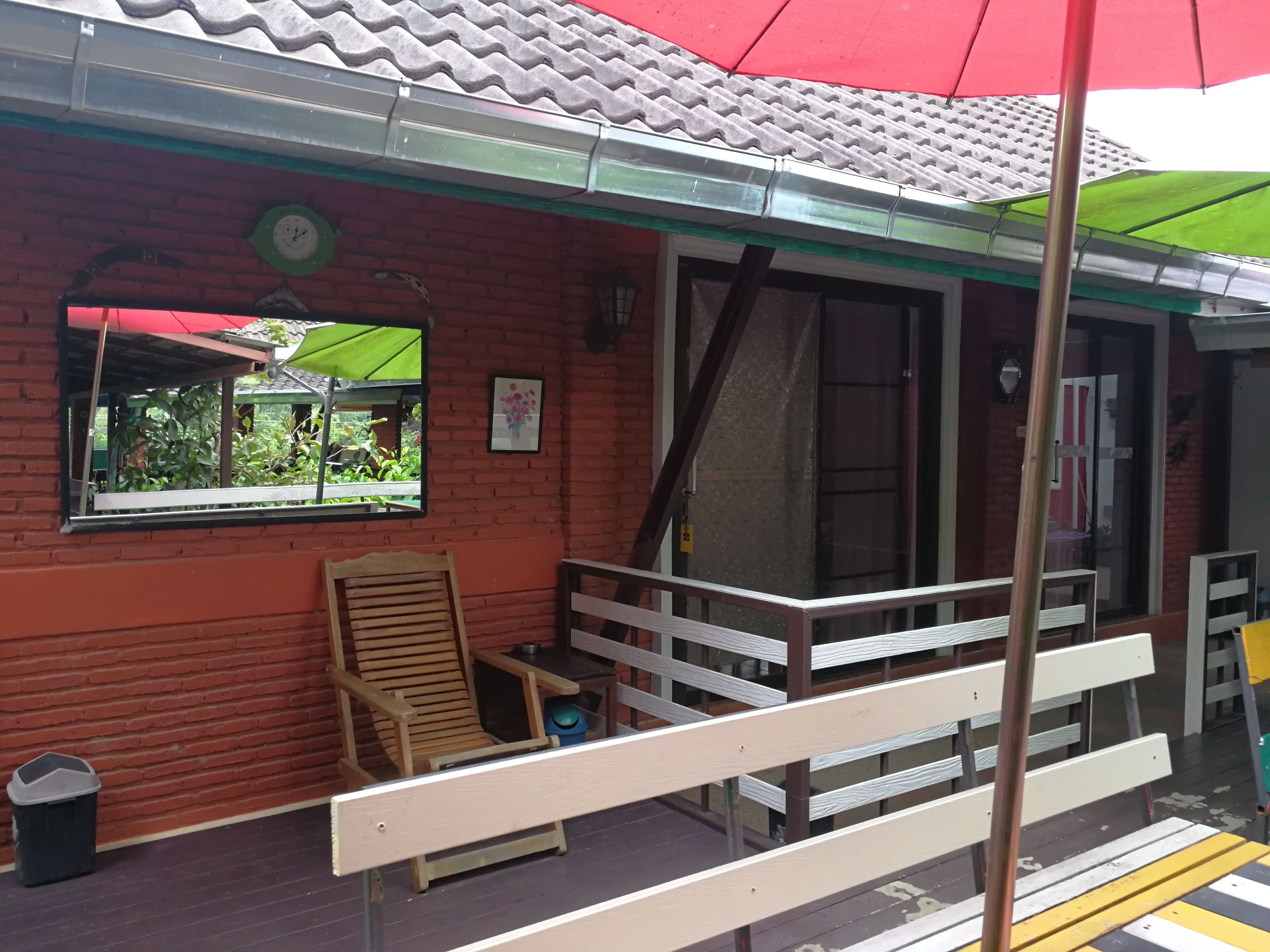 Un edificio de ladrillo rojo con toldo verde, una silla de madera y un banco afuera.