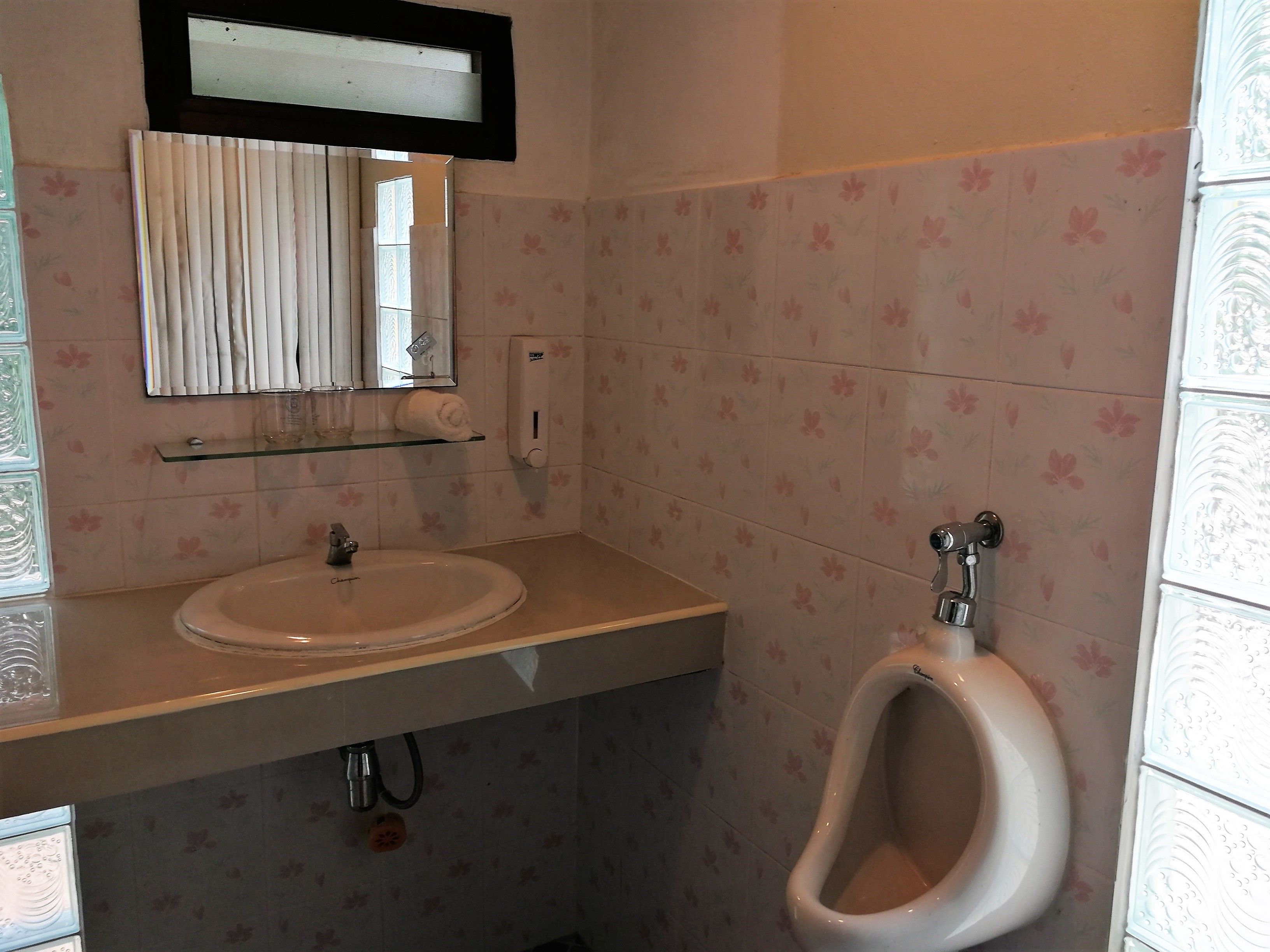 Un baño con lavamanos, espejo y orinal.