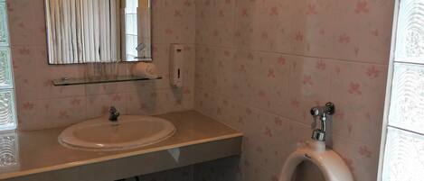 Un baño con lavamanos, espejo y orinal.
