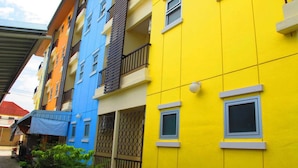 A row of colorful apartment buildings with balconies and small windows. - Mekpufah Apartment (Chonburi)