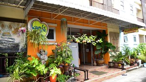 A building with a colorful exterior, potted plants, and a sign indicating it is a restaurant. - Mekpufah Apartment (Chonburi)