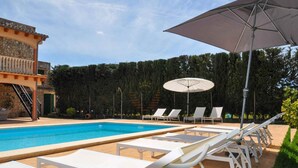 Area piscina con lettini bianchi e un ombrellone grande.