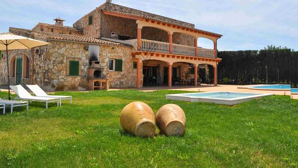 Una villa in pietra con piscina, area salotto esterna e barbecue.