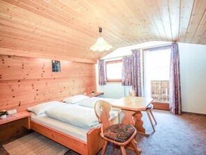 A cozy wooden cabin room with a bed, a table, and a chair.