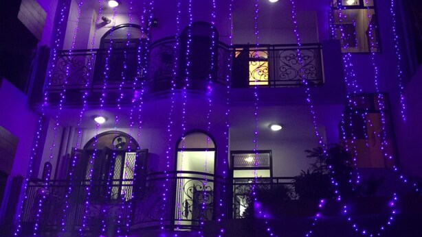 A multi-story building with balconies and windows adorned with purple string lights. - Jagannath B&B Hotel (New Delhi)
