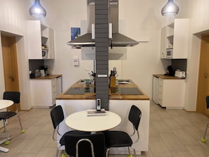 Una cocina compacta con una isla central, dos luces colgantes, microondas y cafetera.
