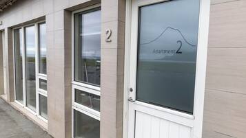 A building facade with a numbered door labeled "Apartment 2" and a window with a mountain view.