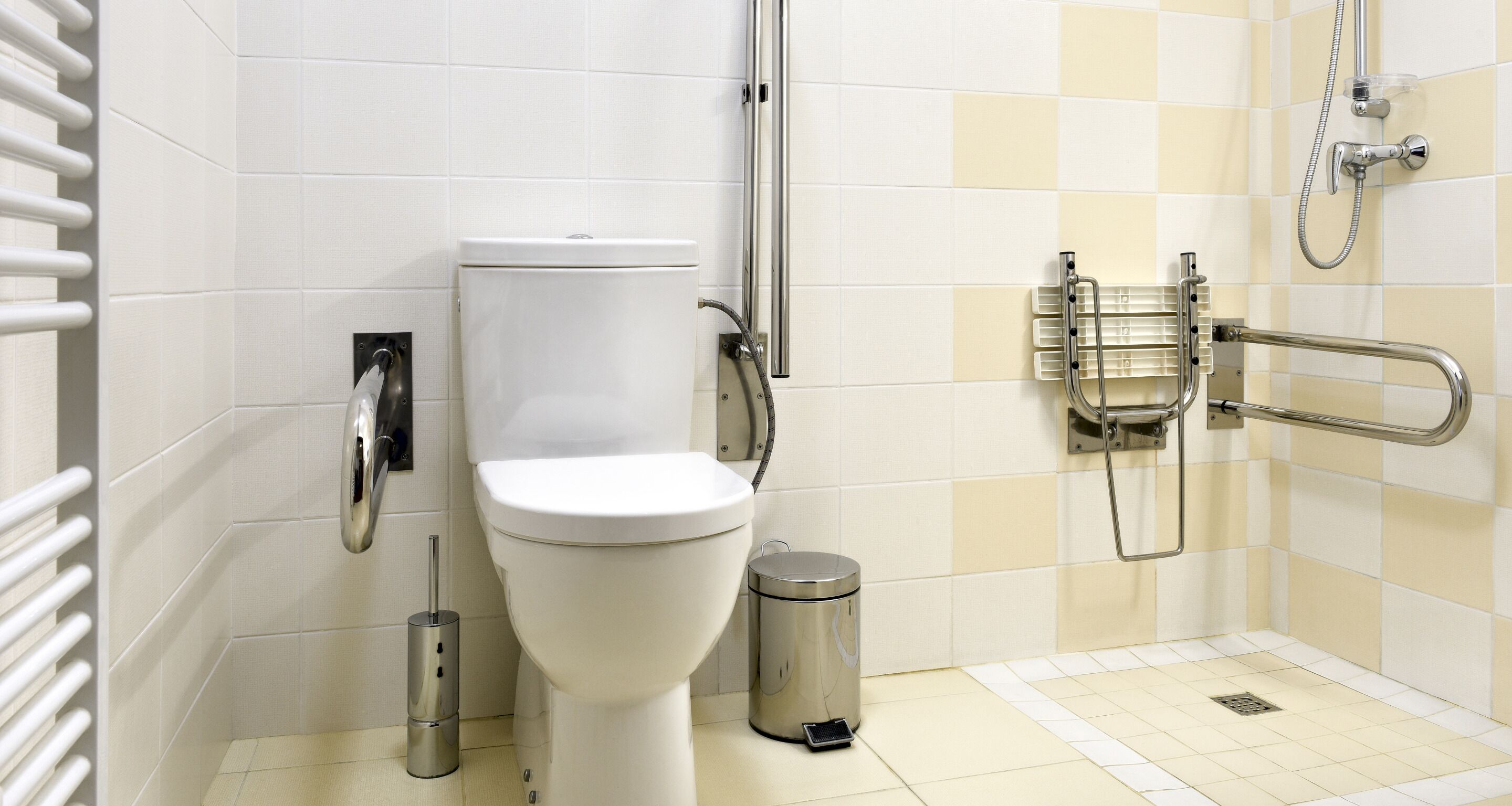 Un baño moderno con inodoro, bidé, secador de manos y un cubo de basura.