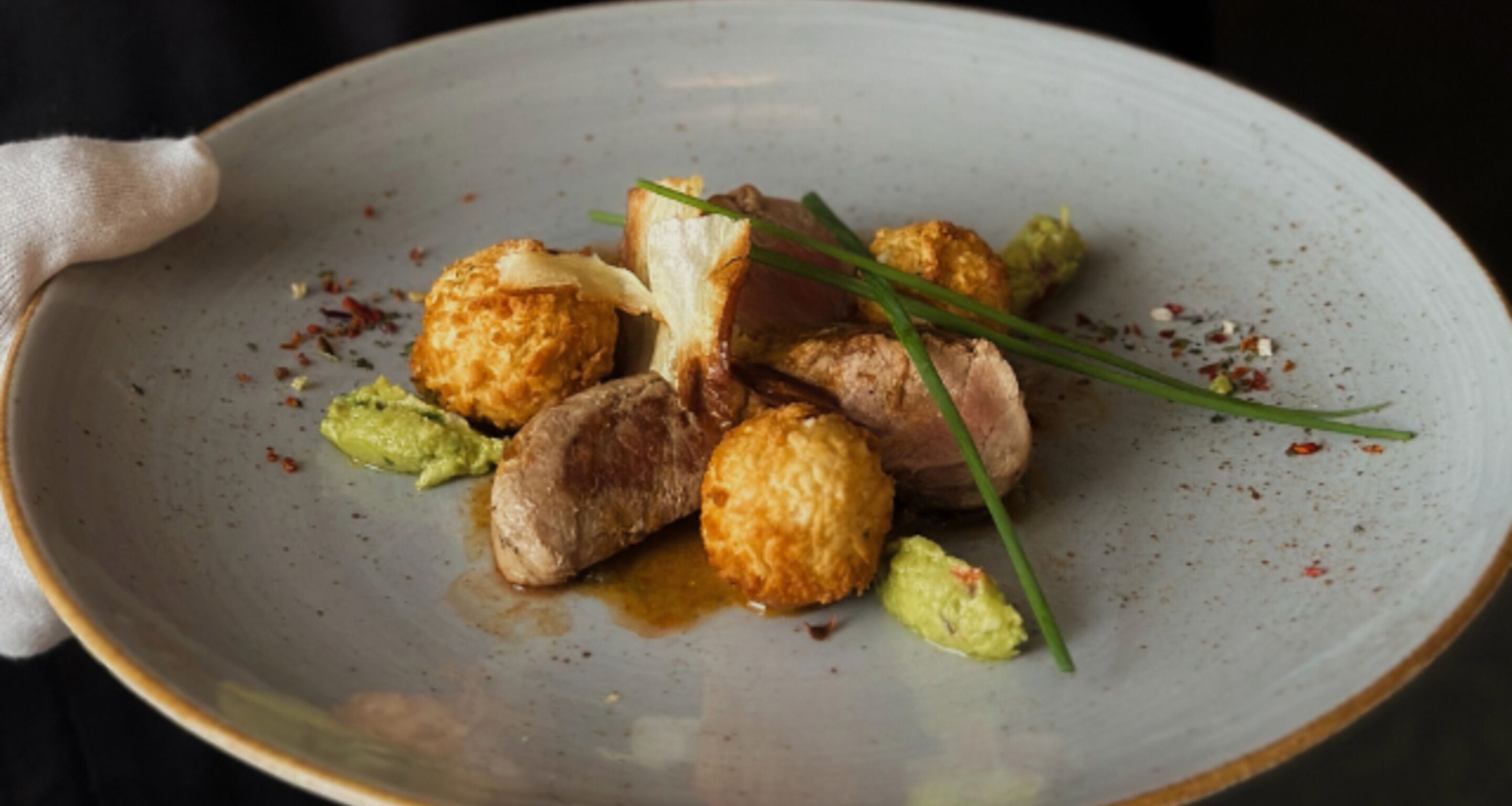 A plate with food, including meat, potatoes, and green garnish.