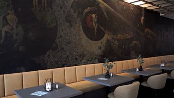A restaurant with booths and tables, a mural on the wall, and a ceiling with lights.