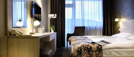 Une chambre d’hôtel comprenant un lit, un bureau avec un téléphone, une chaise, un bol et un miroir.