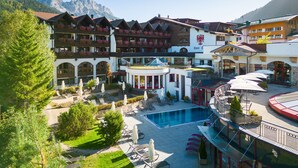 Een hotel met een zwembad, terras en uitzicht op de bergen.