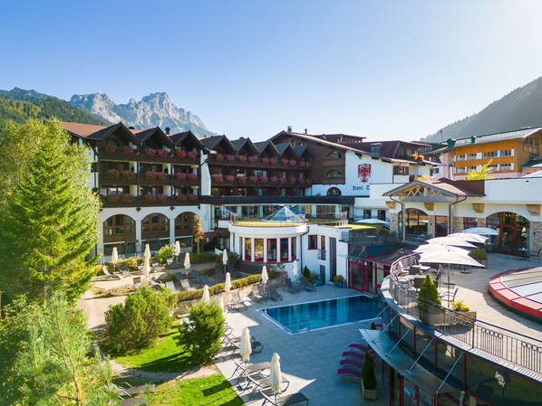 A hotel with a pool, outdoor seating, and mountain views.