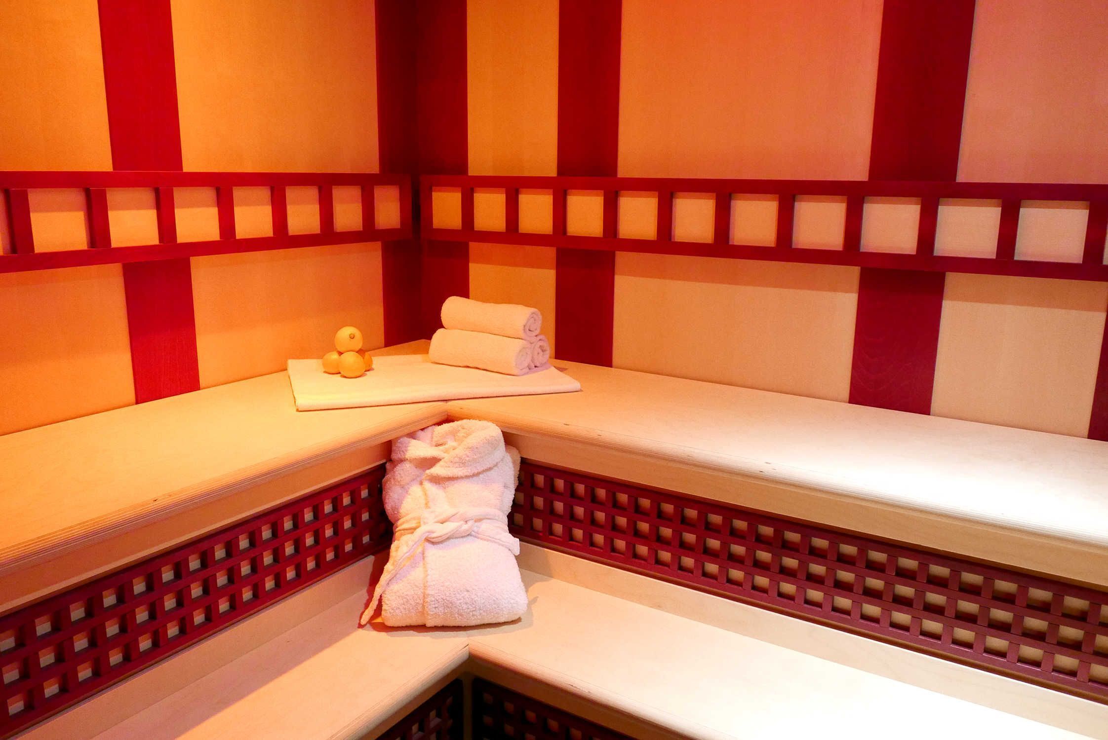 Ein Spa-Raum mit einer Bank, Handtüchern und einer Wand mit Gittermuster.