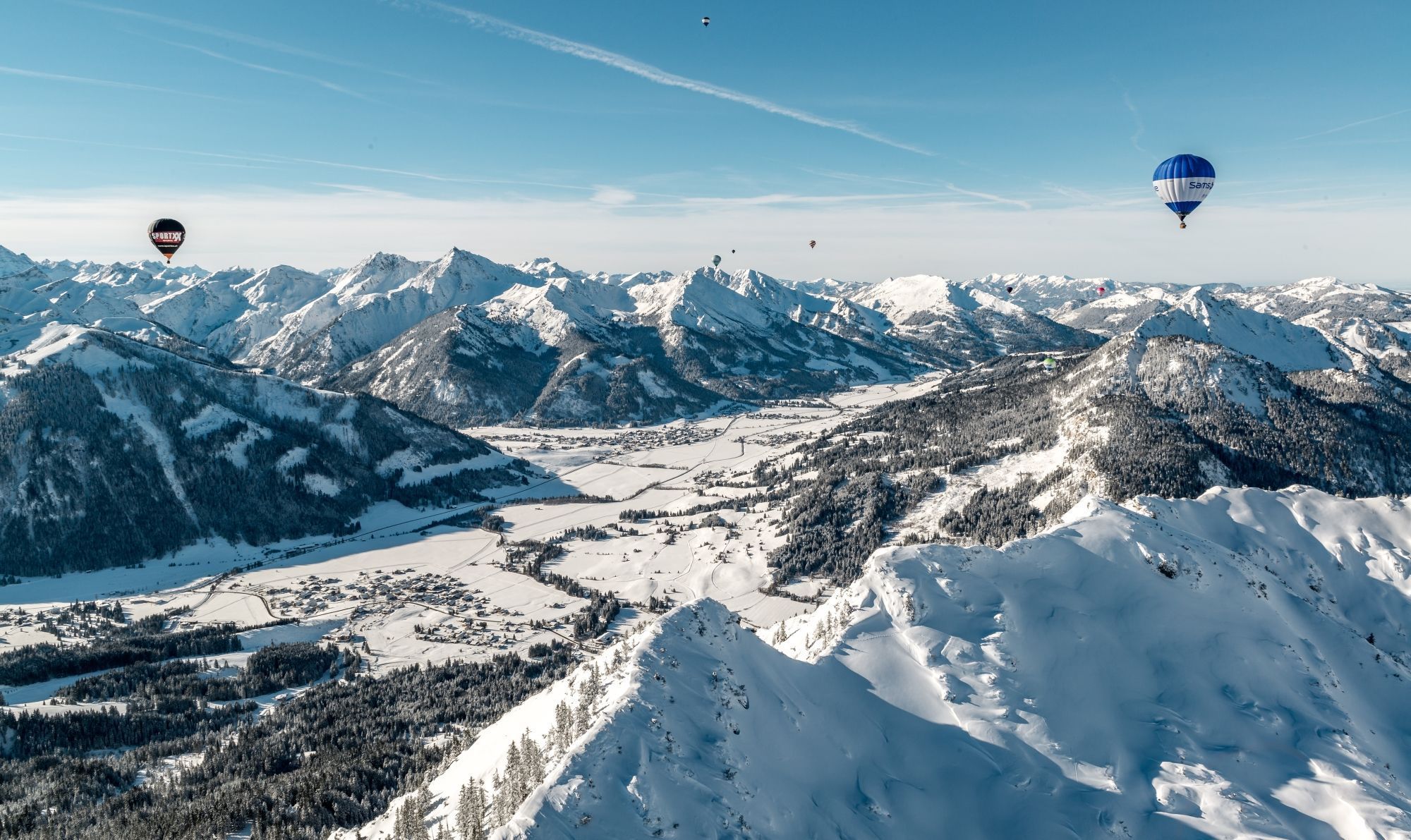 Eine gebirgige Landschaft mit schneebedeckten Gipfeln und einem Tal darunter.