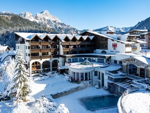 A hotel with multiple balconies, a pool, and a mountainous backdrop.
