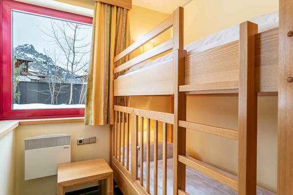 Habitación con literas, ventana, calentador y una pequeña mesa.