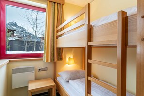 Habitación con literas, ventana, calefacción y lámpara de noche.