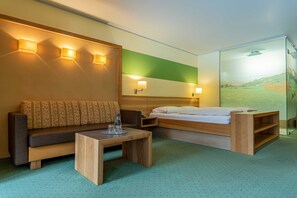 Habitación de hotel moderna con sofá, cama, una mesita y un separador de vidrio con vistas.
