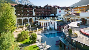 A hotel with a pool, outdoor seating, and mountain views.