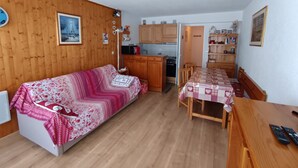A cozy living room with a sofa, a dining table, and a kitchen area. - Renovated studio, 5 pers, near slopes, pets allowed (Montgenèvre)