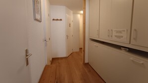 A narrow hallway with wooden flooring, white walls, and a white door at the end. - Renovated studio, 5 pers, near slopes, pets allowed (Montgenèvre)