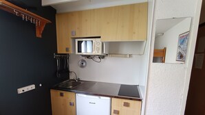 Pieni, käytännöllinen keittiö, jossa on valkoinen astianpesukone, puukehikot, mikroaaltouuni ja pesuallas.