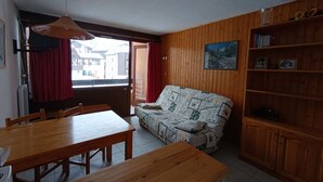 Un soggiorno accogliente con un divano di legno, un tavolo da pranzo e una libreria.