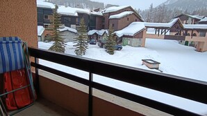 Un villaggio montano innevato con edifici in legno tradizionali e una vista chiara da un balcone.