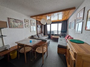 A compact living space with a dining table, sofa, and a TV.